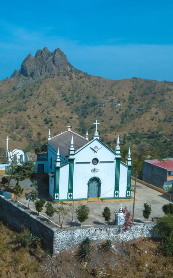 Hilltop church below a mountain peak